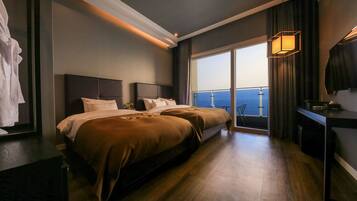 A hotel room with a large bed, a desk, and a view of the ocean.