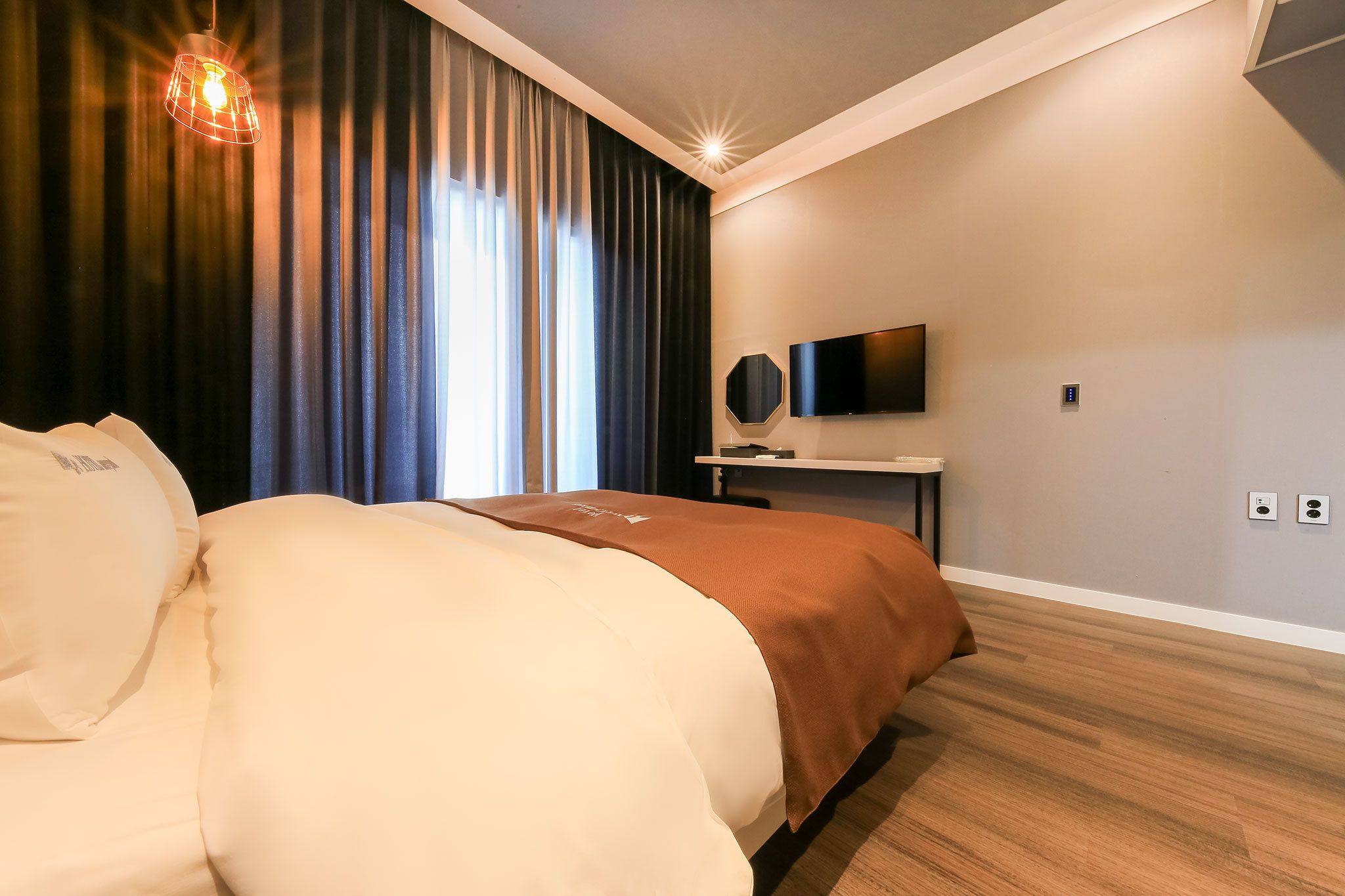 A modern hotel room with a large bed, a flat-screen TV, and a desk.