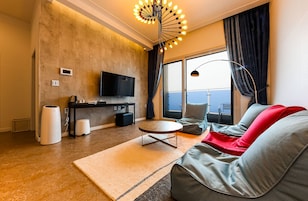 A modern living room with a flat-screen TV, a round coffee table, and a sofa with red cushions.