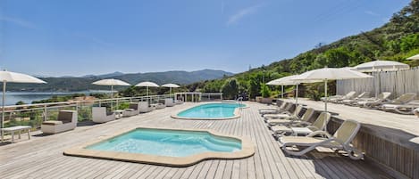 Una piscina al aire libre de temporada, sombrillas, tumbonas