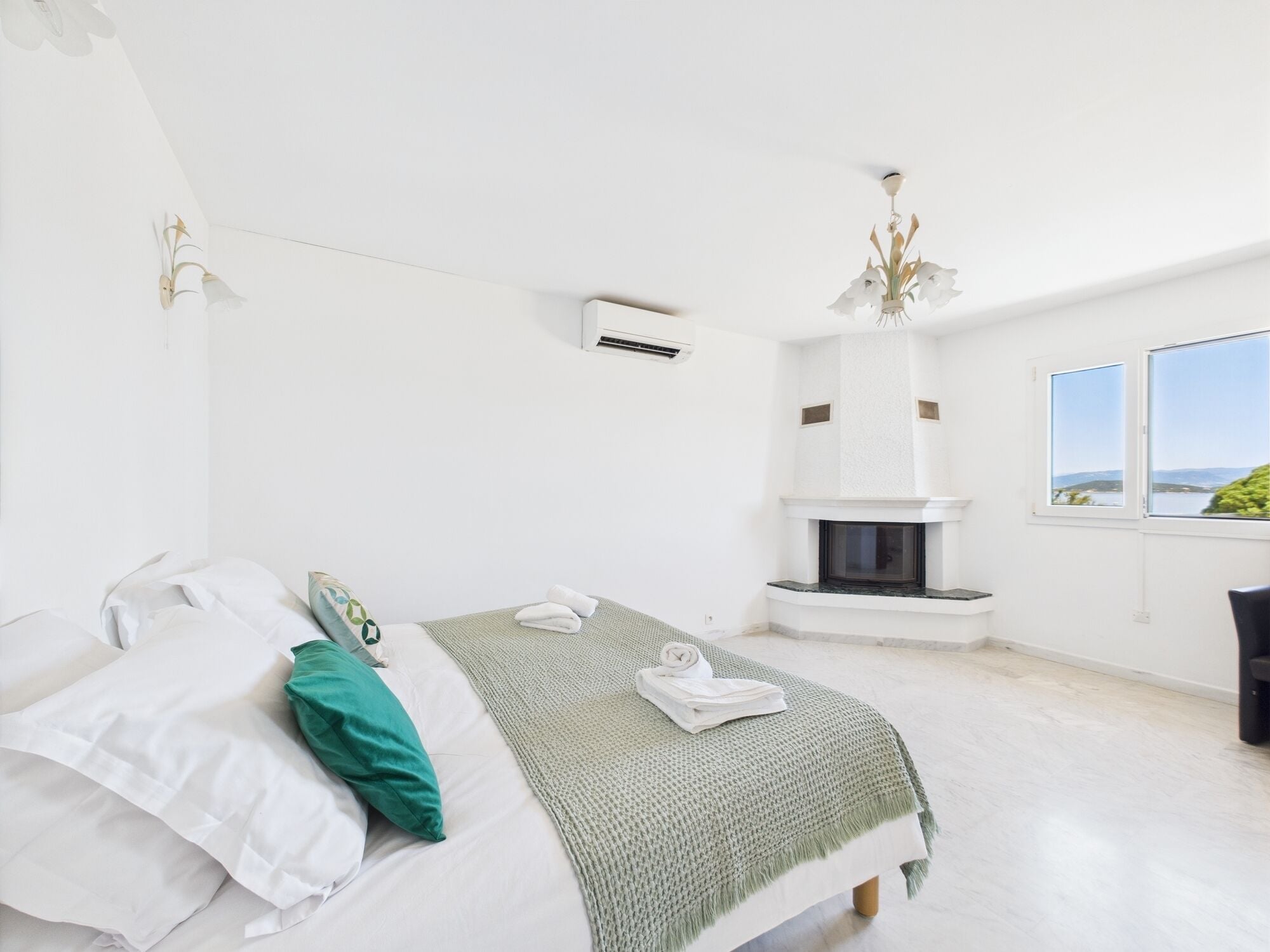 Un dormitorio con cama, chimenea y vistas al exterior.