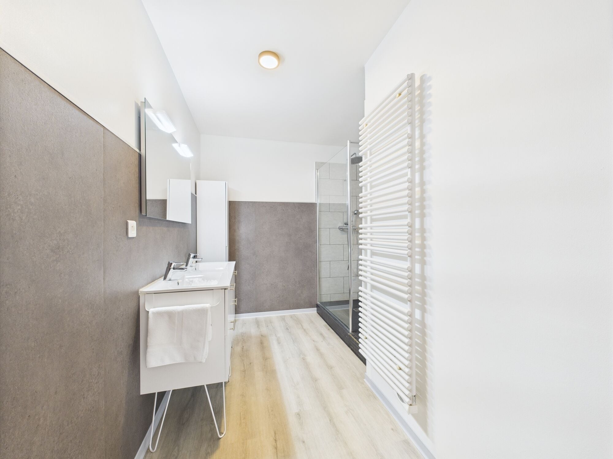 Un baño moderno con ducha, lavamanos y espejo.