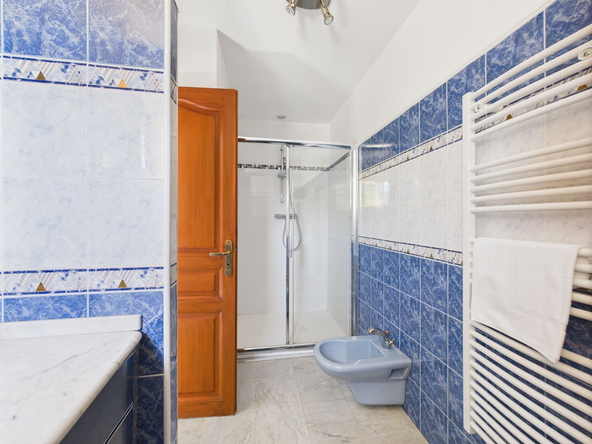 A bathroom with a shower, toilet, and a towel rack.