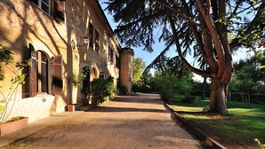 A gravel path leading to a building with arched windows and a brick facade. - Seventeenth-century Villa Giulia with panoramic swimming pool, +15 beds ((PERUGIA))