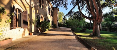 A gravel path leading to a building with arched windows and a brick facade.