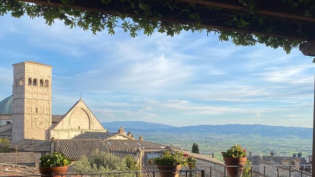 An outdoor terrace with a table set for two, overlooking a historic building with a tower and a dome. - Seventeenth-century Villa Giulia with panoramic swimming pool, +15 beds ((PERUGIA))