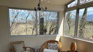 Una habitación soleada con ventanas amplias, muebles de mimbre y suelo de baldosas.