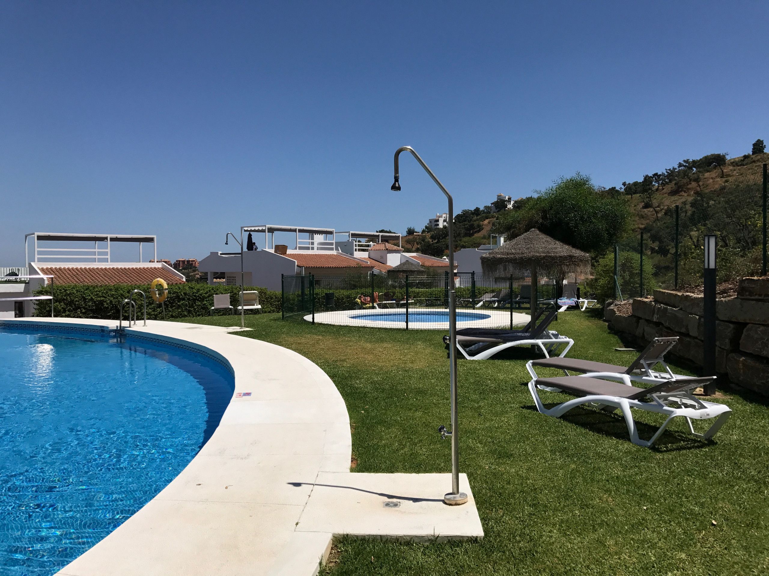 A pool area with two pools, lounge chairs, and a gazebo.