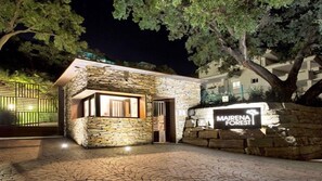 A stone building with a sign reading "MAIRENA FOREST" at night.