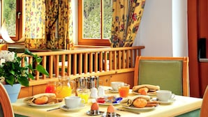 Ein Frühstückstisch gedeckt mit Eiern, Toast, Saft und Kaffee, mit Blick auf einen Wald durch das Fenster.