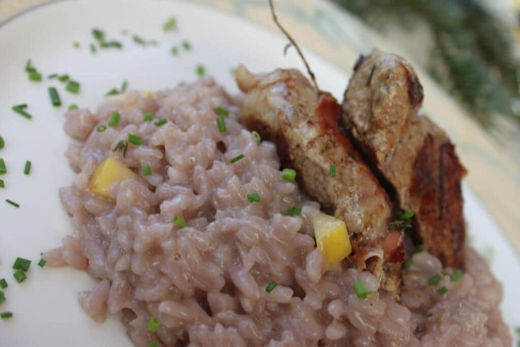 A plate with risotto and grilled meat, garnished with herbs.