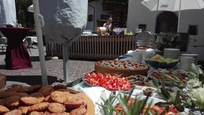 Ein reichhaltiges Buffet mit verschiedenen Speisen, darunter Spieße, eine große runde Torte und eine Schale Gebäck.