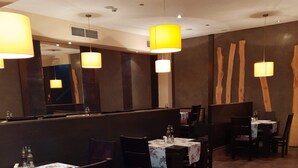 Interior de restaurante com cabines, mesas e luminárias pendentes.