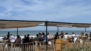 An outdoor dining area with tables and chairs, overlooking the ocean.