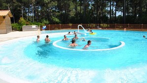 A swimming pool with a wooden deck and a fenced area.