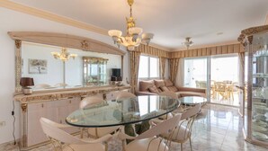 A dining area with a glass table and chairs, a large mirror, and a chandelier. - Apartamaneto Joya 4 by Costa CarpeDiem (Calp)