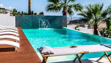 Una piscina al aire libre, sillones reclinables de piscina