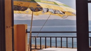 Une chambre avec vue sur la mer, un parasol de plage et une fenêtre donnant sur l’océan.