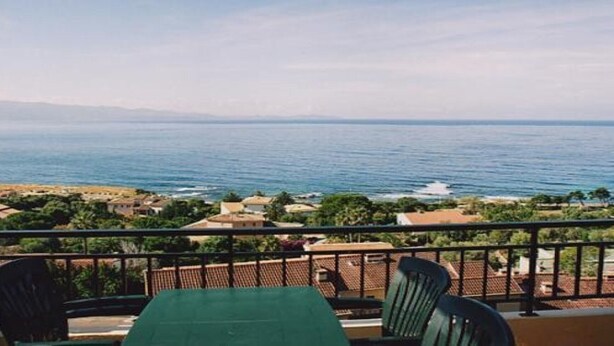 Un balcon avec une table et des chaises donnant sur une vue sur la côte.