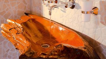 Ein Waschbecken aus Holz mit Wasserhahn und zwei Glasbechern, die an der Wand befestigt sind.