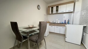 A modern kitchen with white cabinets, a glass dining table, and two chairs.