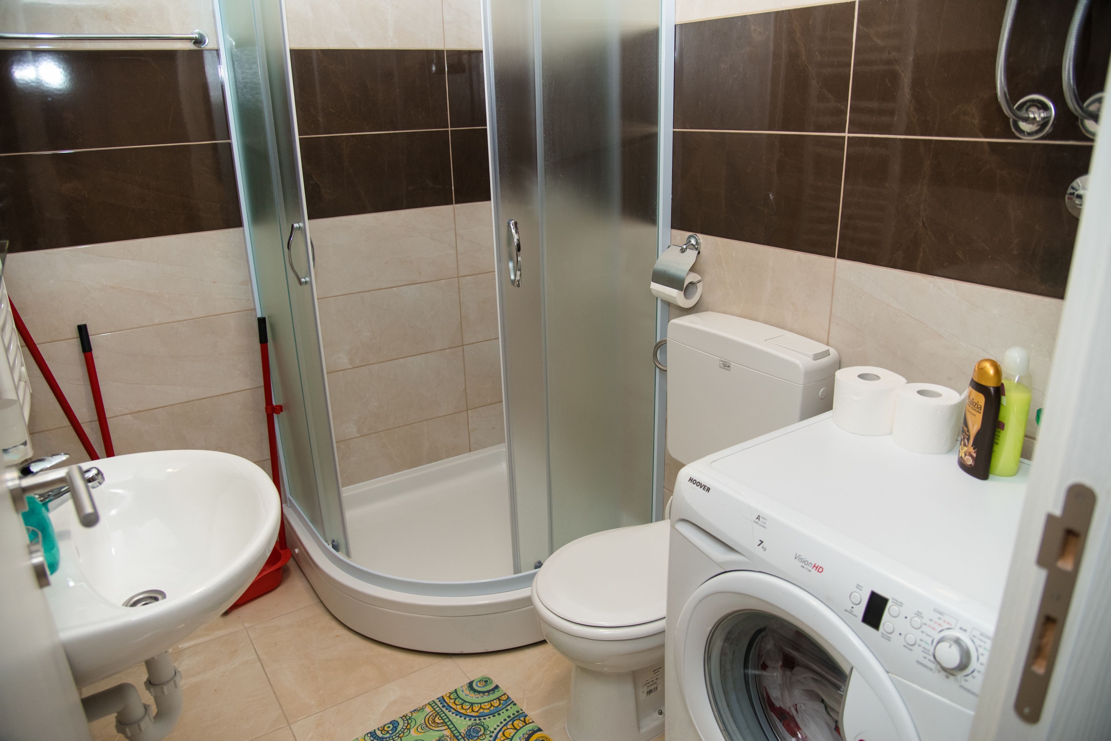 Ein Badezimmer mit Duschkabine, Toilette, Waschbecken und Waschmaschine.