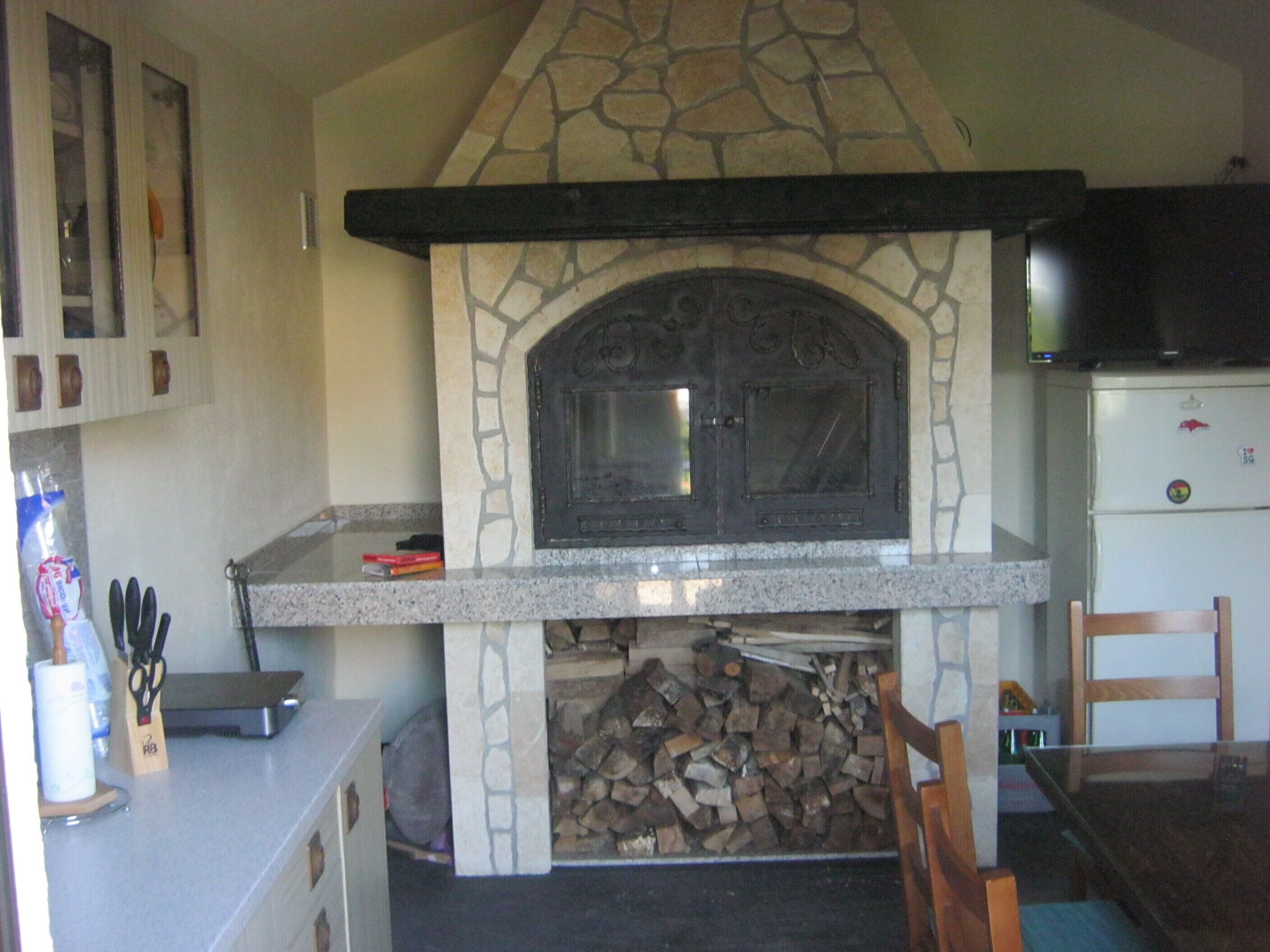 A stone fireplace with a modern kitchen adjacent.