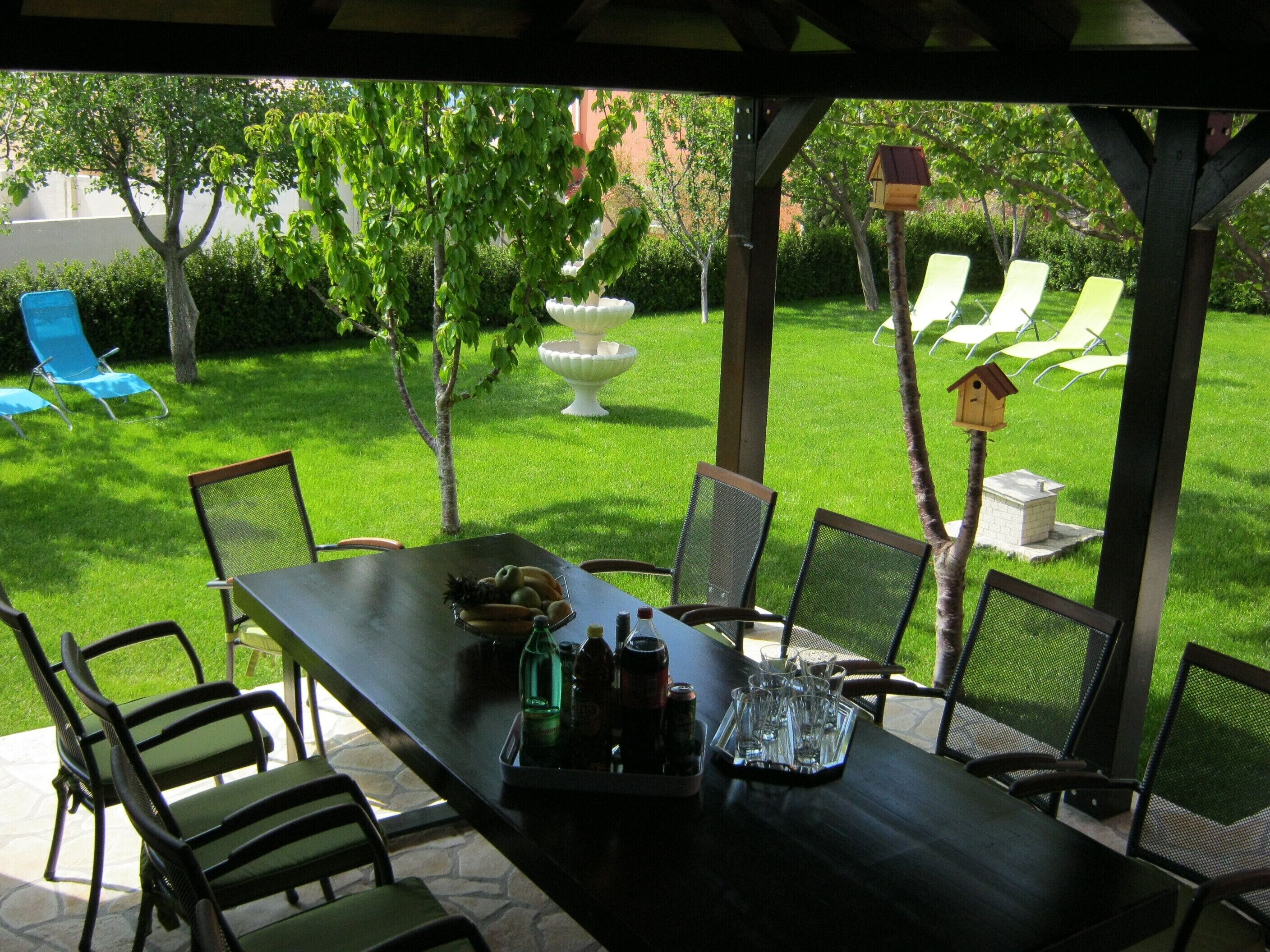 Un patio al aire libre con una mesa preparada para comer, rodeado de sillas.