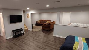 A spacious living area with a flat-screen TV, a sofa, and a bed. - EAA AirVenture - 5 Bedroom 4 bath 2 Story home at the end of a cul de sac (Appleton)
