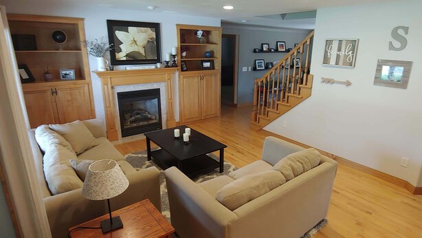 A living room with a fireplace, wooden furniture, and a staircase. - EAA AirVenture - 5 Bedroom 4 bath 2 Story home at the end of a cul de sac (Appleton)