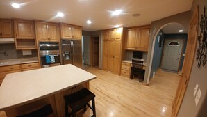 A spacious kitchen with wooden cabinets, stainless steel appliances, and a large island. - EAA AirVenture - 5 Bedroom 4 bath 2 Story home at the end of a cul de sac (Appleton)