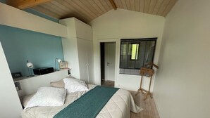 A bedroom with a bed, a bedside table with a lamp, a wooden hanger, and a window with blinds. - House / Villa - Cap ferret (Lège-Cap-Ferret)