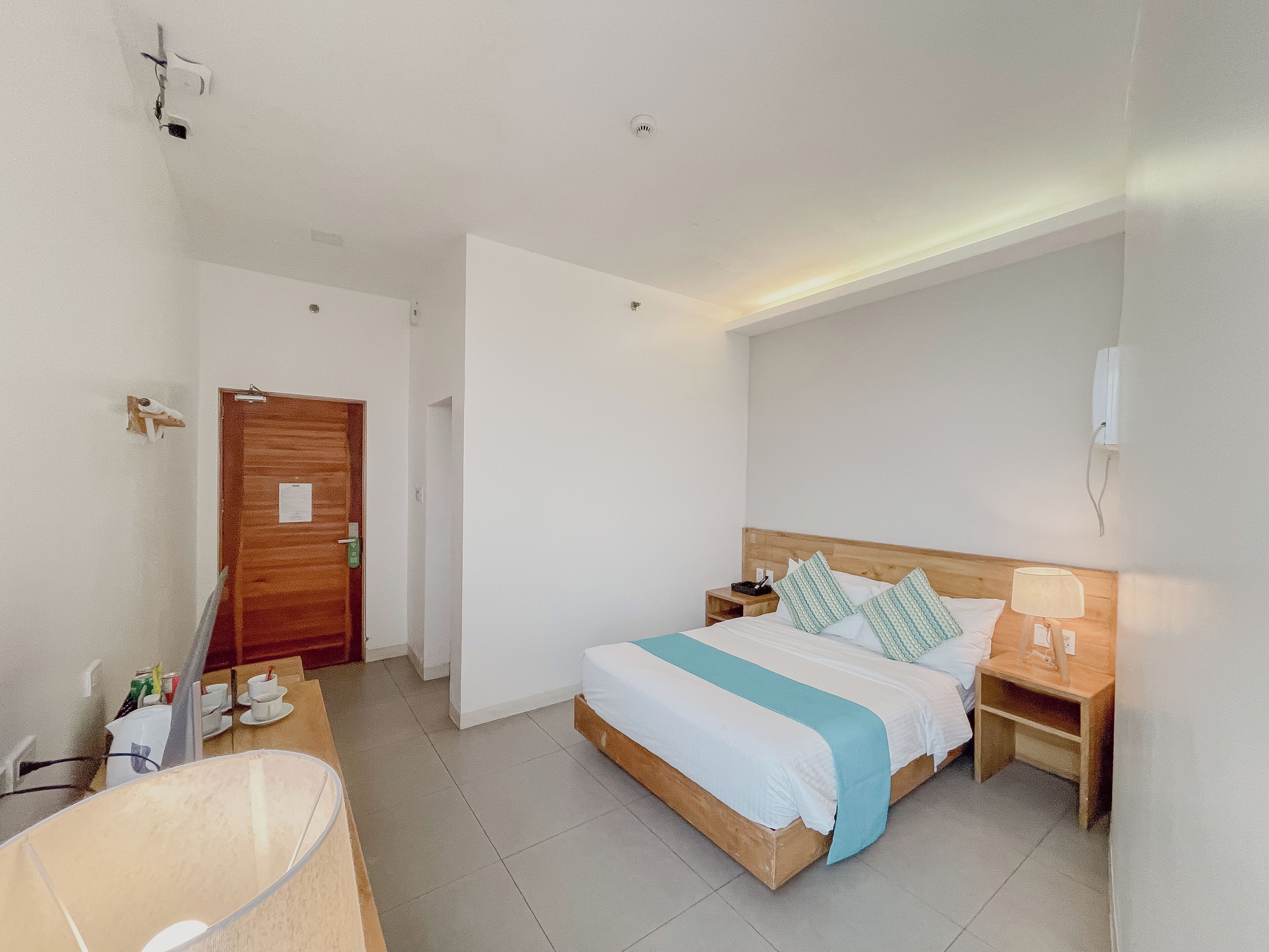 Una habitación de hotel con cama, mesitas de noche, un escritorio y una silla.