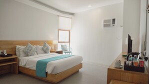 Una habitación de hotel moderna con una cama de madera, un escritorio con una silla, una mesita con una taza y una botella, y una ventana con persianas.