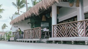 A restaurant with a thatched roof, outdoor seating, and a view of palm trees.