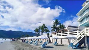 Una playa con sombrillas, sillas y un edificio con escaleras.