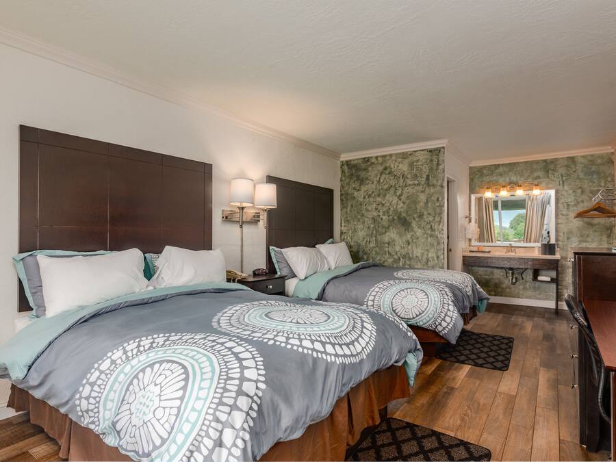 A bedroom with two beds, a desk, and a vanity with a mirror.