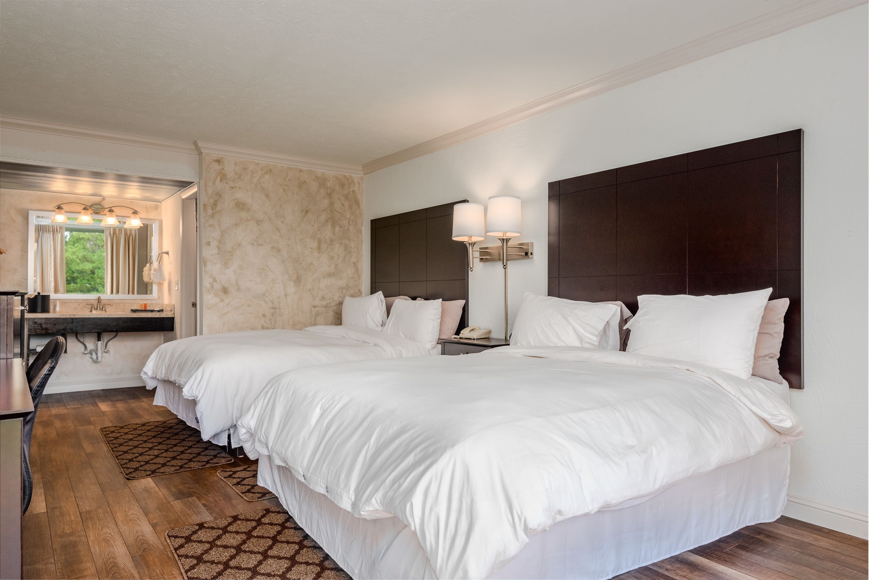 Una habitación de hotel con una cama grande, un escritorio y un tocador con espejo.