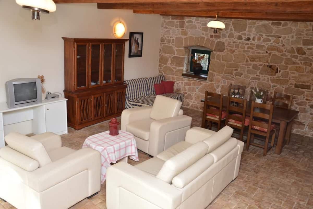 Una sala de estar acogedora con una pared de piedra, un mueble de madera, un televisor y un sofá.