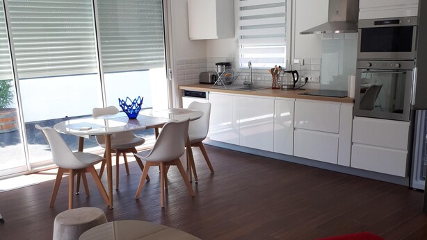 A modern kitchen with white cabinets, a stainless steel range hood, and a built-in oven. - Pretty little house in La Tremblade (La Tremblade)