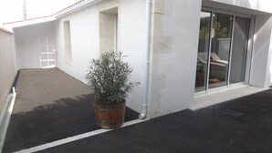 A building with a white exterior, a potted plant in the foreground, and a clear view of the adjacent property through a glass door. - Pretty little house in La Tremblade (La Tremblade)
