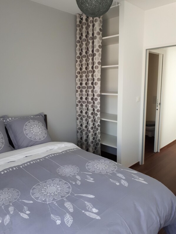 Une chambre à coucher comprenant un lit, une armoire et une porte donnant sur une autre pièce.