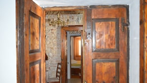 Una puerta de madera que da a una habitación con pared de piedra y una cama con ventana.