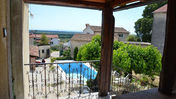 Un balcón con vistas a una piscina, un jardín y edificios circundantes.