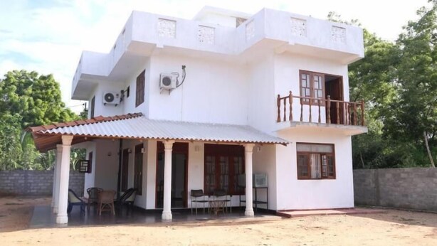 Edifici blanc de dues plantes amb un balcó, un porxo cobert i una petita zona d'estar a l'exterior.