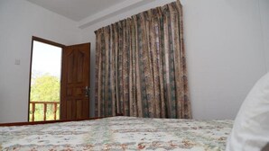 Un dormitori amb un llit, una porta i vistes a la verdura a l'exterior.