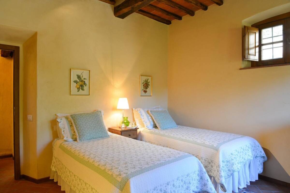 A bedroom with two beds, a nightstand with a lamp, and two framed pictures on the wall.