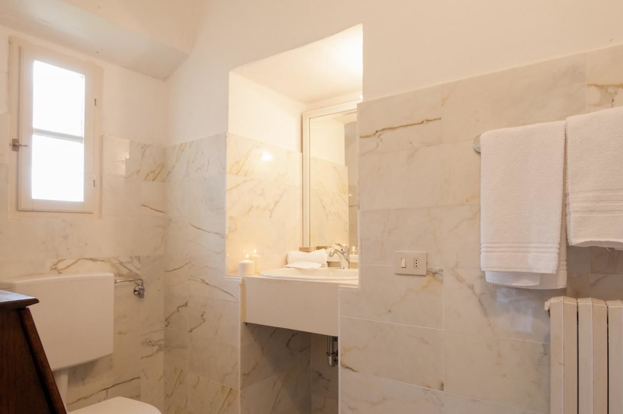 A bathroom with marble walls, a toilet, a sink, and a mirror.