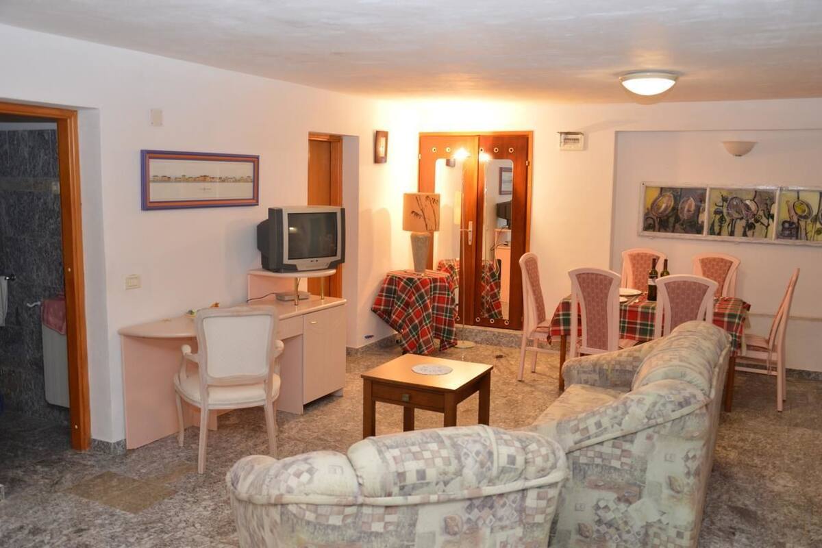 A cozy living room with a sofa, chairs, a small table, a television, and a fireplace.