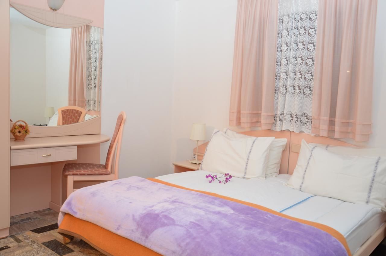 A bedroom with a bed, a desk, a chair, a mirror, and a nightstand.